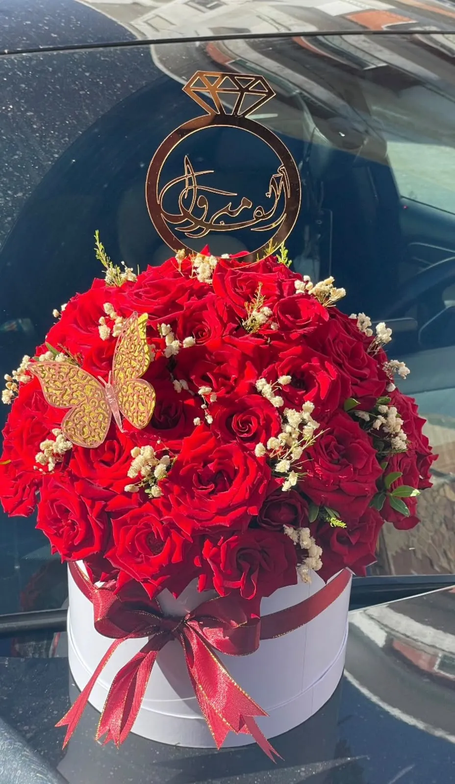 Boîte de roses rouges et papillons dorés